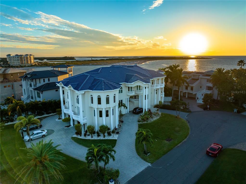 An aerial view of a large, multi-story coastal mansion with a blue roof at sunset — 774 NINA DRIVE, TIERRA VERDE, FL