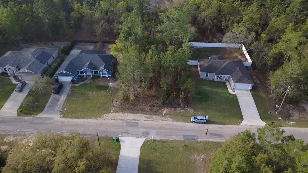 An aerial view shows a vacant wooded lot situated between two single-family suburban houses — 2282 W WAVECREST DRIVE, DUNNELLON, FL
