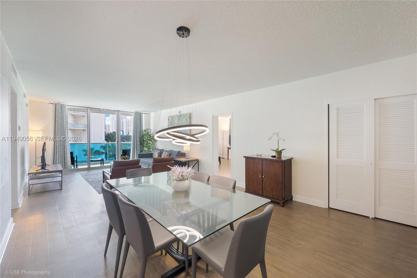 A dining area with a glass table and modern chandelier opens into a living room — 4001 S Ocean Dr # 3B, Hollywood FL 33019, HOLLYWOOD, FL