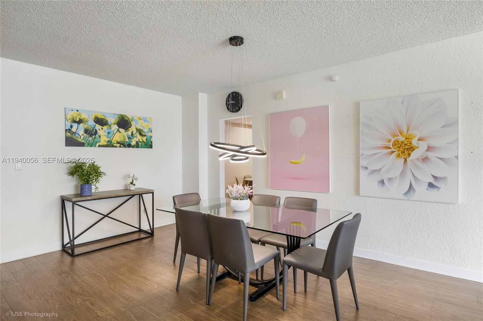 A dining room features a glass table, gray chairs, modern lighting, and wall art — 4001 S Ocean Dr # 3B, Hollywood FL 33019, HOLLYWOOD, FL