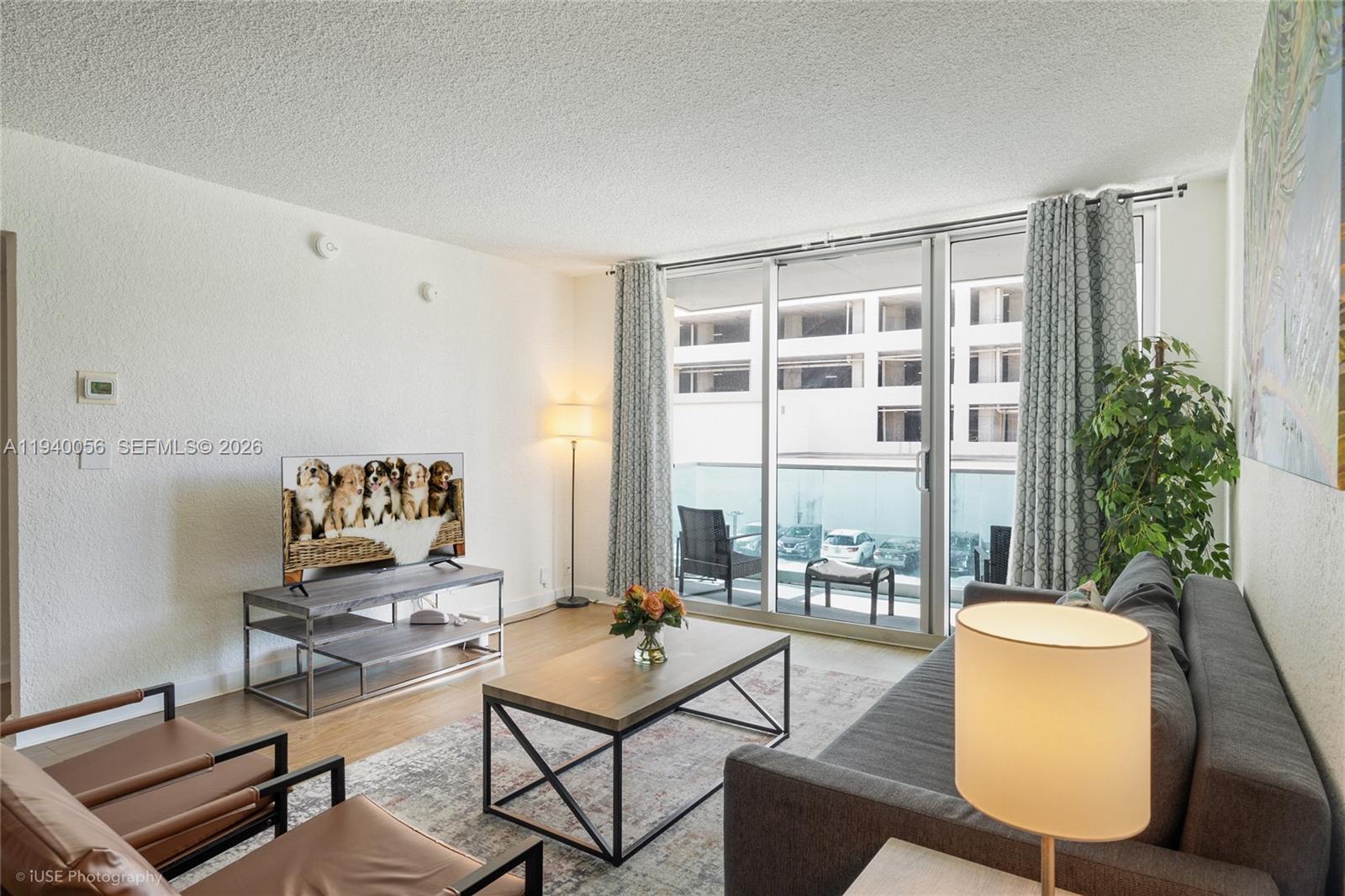 A living room features a grey sofa, a coffee table, and a sliding glass door — 4001 S Ocean Dr # 3B, Hollywood FL 33019, HOLLYWOOD, FL