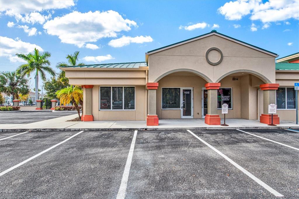 A single-story commercial building with a tan facade, arched entryway, and a paved parking lot — 234 N RHODES AVENUE UNIT 108, SARASOTA, FL