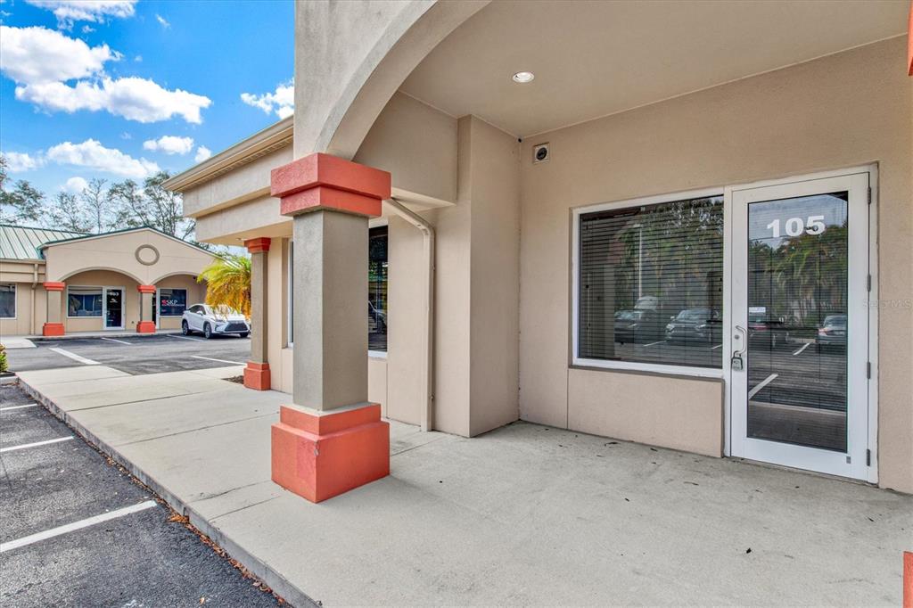 The exterior view shows a commercial building entrance with a concrete walkway and glass door — 234 N RHODES AVENUE UNIT 108, SARASOTA, FL