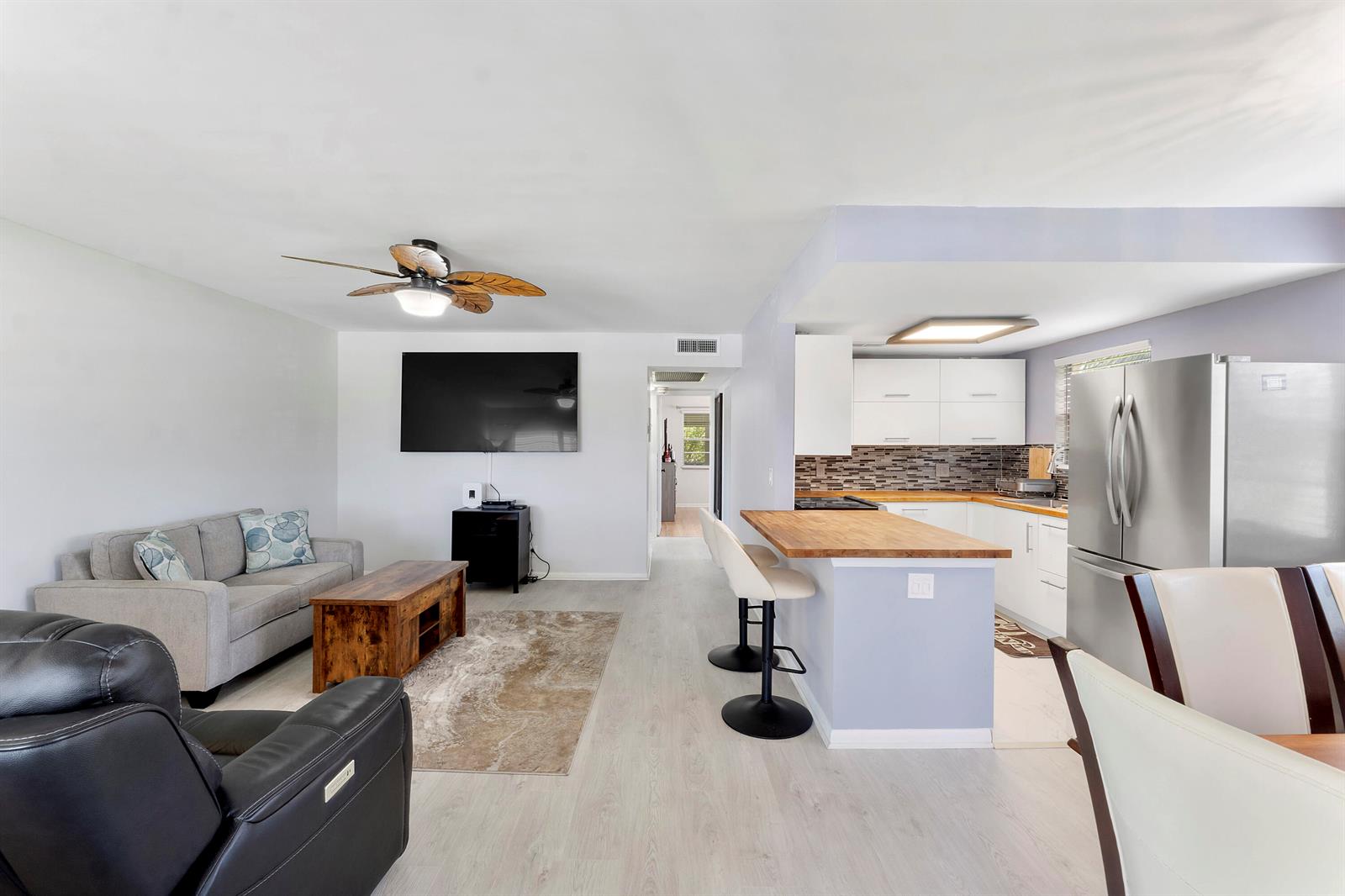 An open-concept living room and kitchen featuring light wood flooring and a breakfast bar — 253 Prescott M, Deerfield Beach FL 33442, DEERFIELD BEACH, FL