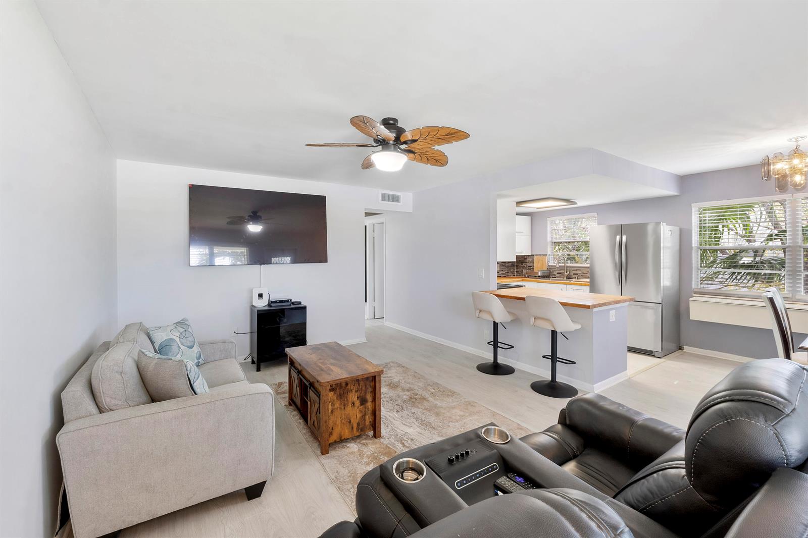 A living room with a sofa, coffee table, and television opens to a kitchen with bar seating — 253 Prescott M, Deerfield Beach FL 33442, DEERFIELD BEACH, FL