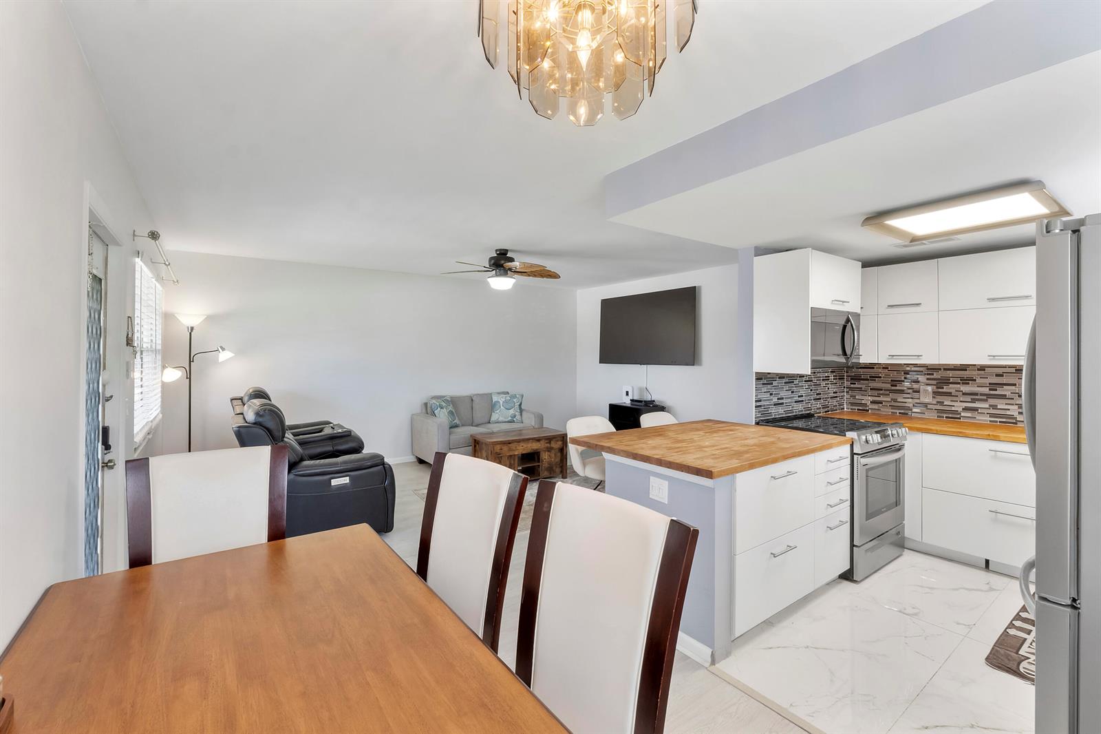 An open-concept living area features a dining table, kitchen island, and white cabinetry — 253 Prescott M, Deerfield Beach FL 33442, DEERFIELD BEACH, FL