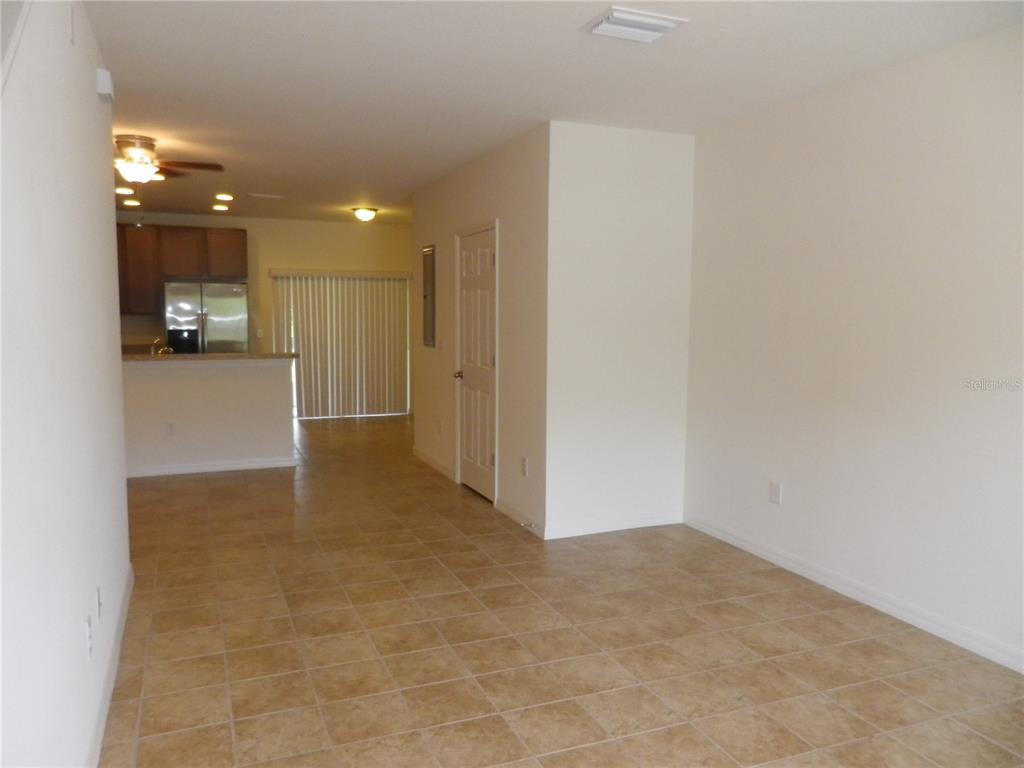 An open-concept living area features beige tile flooring, a kitchen with dark cabinets, and blinds — 15965 FISHHAWK VIEW DRIVE, LITHIA, FL