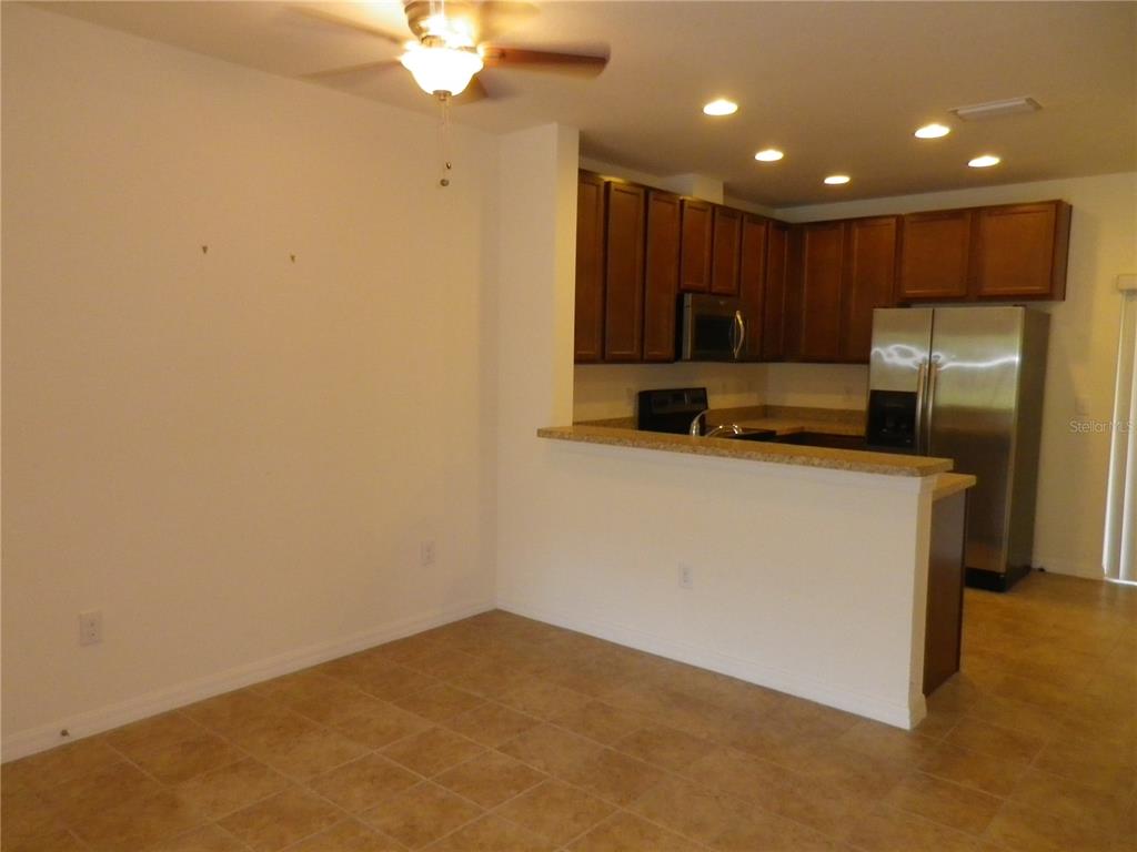 A kitchen with wood cabinets and stainless steel appliances overlooks an open dining area — 15965 FISHHAWK VIEW DRIVE, LITHIA, FL