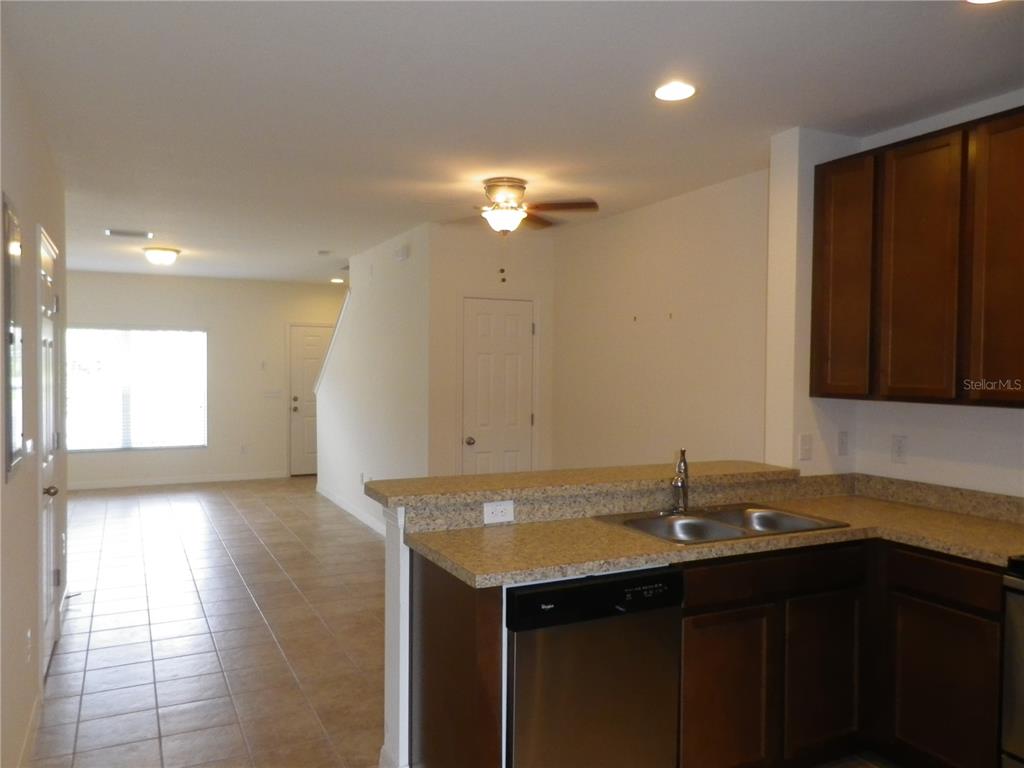 A kitchen with dark wood cabinets and granite countertops overlooks an open living area — 15965 FISHHAWK VIEW DRIVE, LITHIA, FL