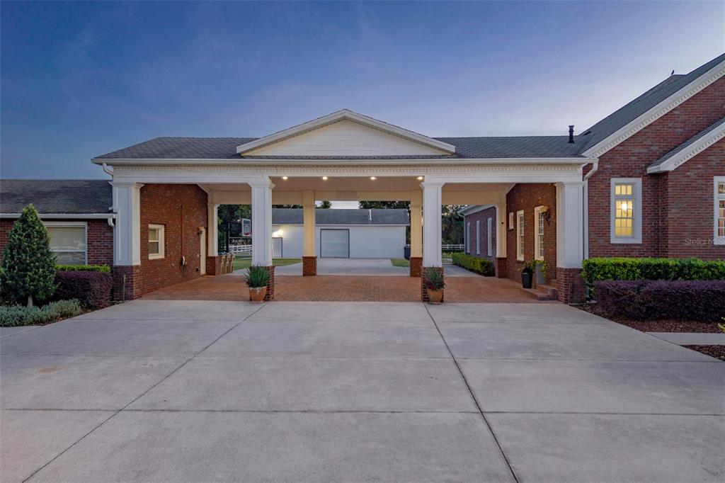 A brick house features a large covered porte-cochere leading to a detached garage — 2780 VICKIE COURT, KISSIMMEE, FL