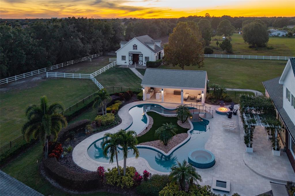 An aerial view shows a backyard with a freeform pool, hot tub, and covered patio — 2780 VICKIE COURT, KISSIMMEE, FL