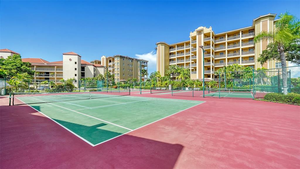 A tennis court with a green surface and red perimeter sits before large apartment buildings — 5100 JESSIE HARBOR DRIVE UNIT 504, OSPREY, FL