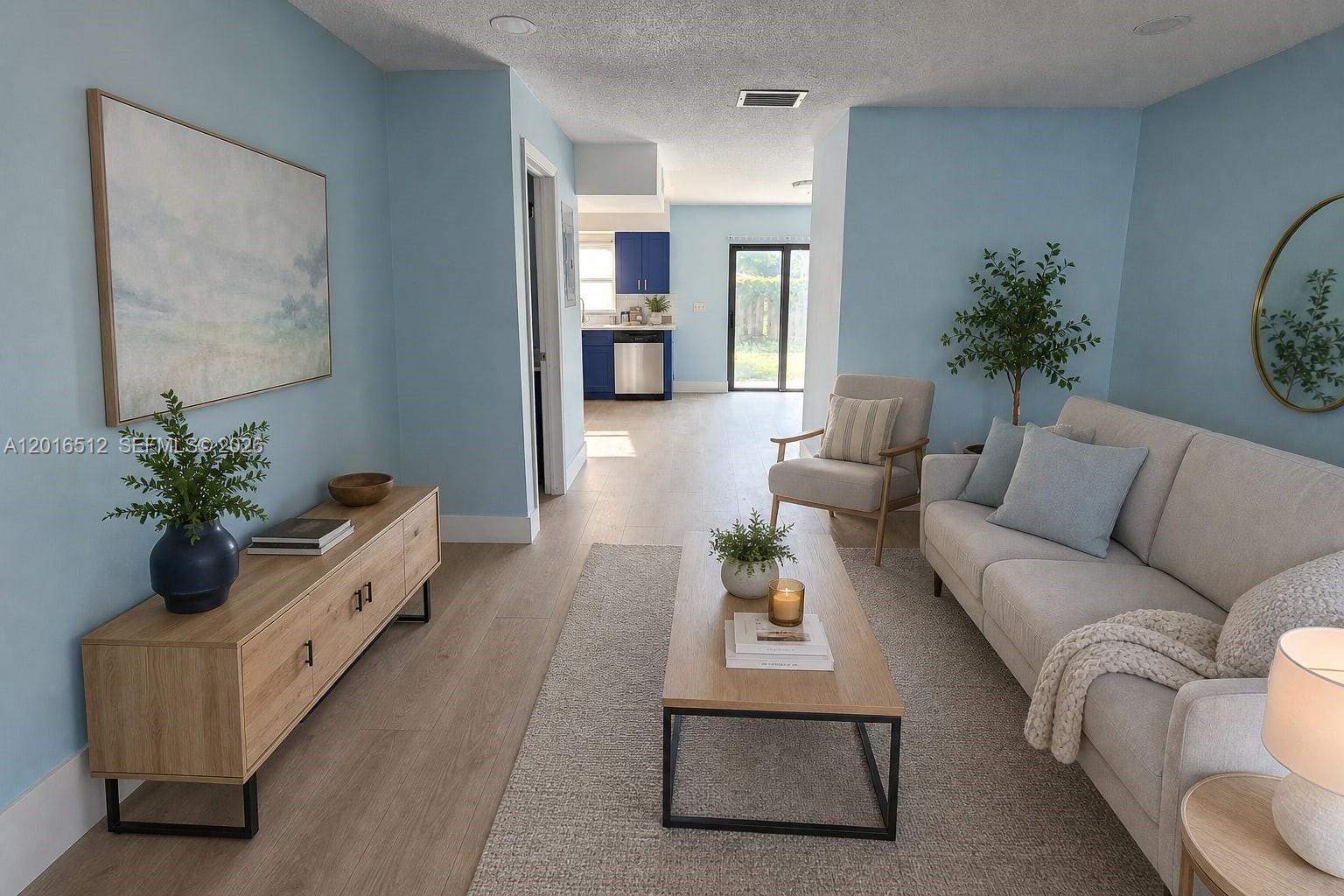 A living room with light blue walls, wood-look flooring, a sofa, and a kitchen beyond — 2262 NW 59th Way # 2262, Lauderhill FL 33313, LAUDERHILL, FL