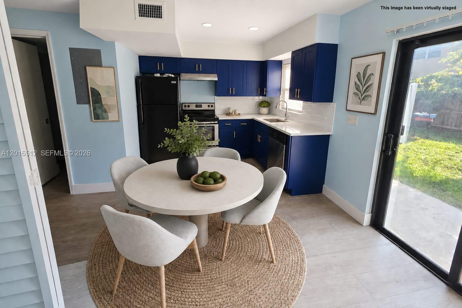 This kitchen and dining area features blue cabinets, a round table, and a sliding glass door — 2262 NW 59th Way # 2262, Lauderhill FL 33313, LAUDERHILL, FL