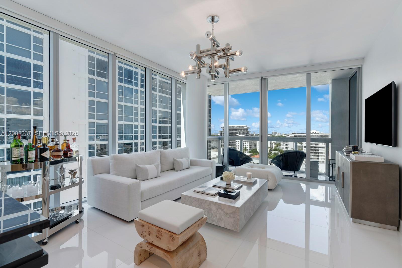 A modern living room features a white sofa, marble coffee table, and floor-to-ceiling windows — 6899 Collins Ave # 1109, Miami Beach FL 33141, MIAMI BEACH, FL