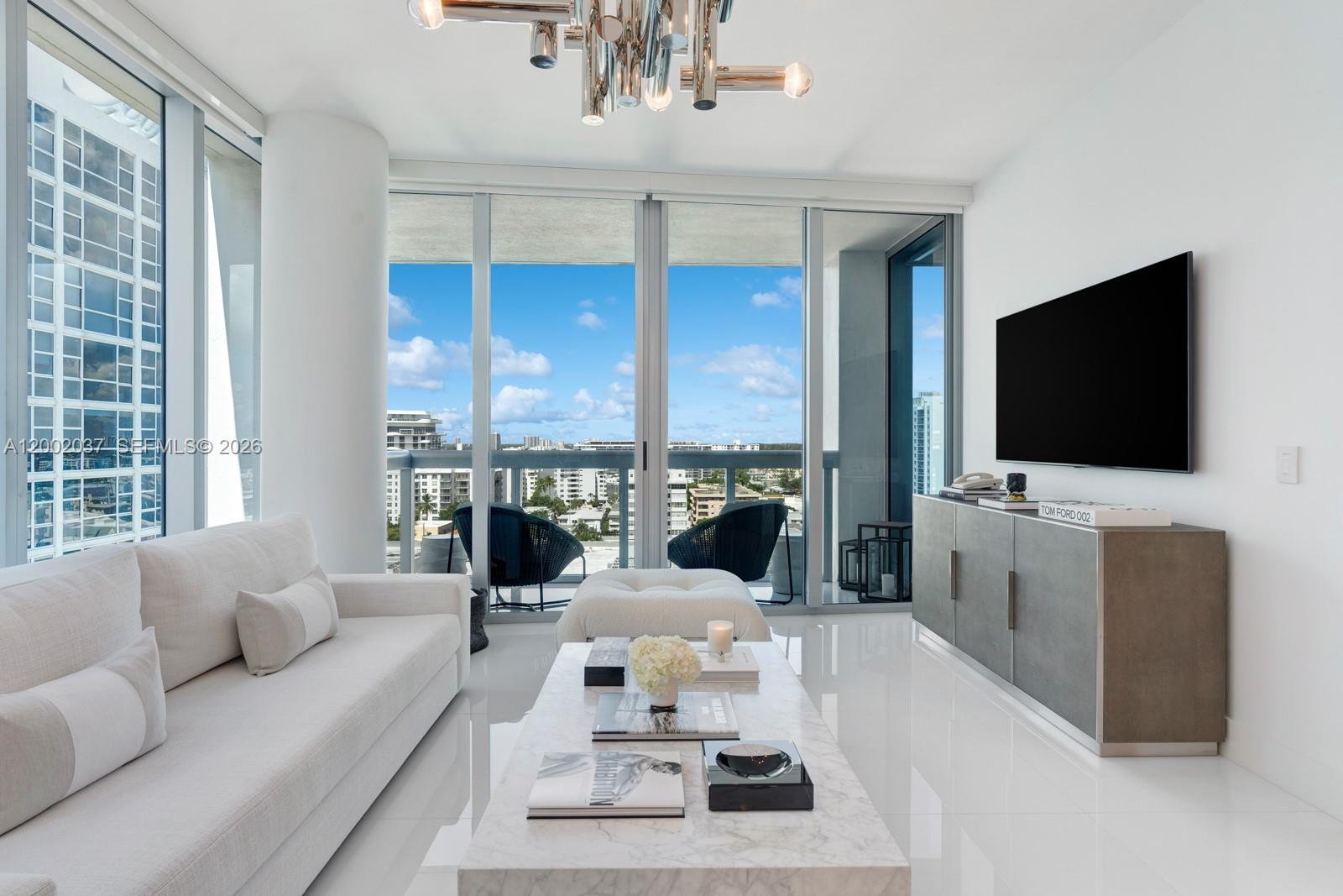 A modern living room features a white sofa, marble coffee table, and floor-to-ceiling balcony windows — 6899 Collins Ave # 1109, Miami Beach FL 33141, MIAMI BEACH, FL