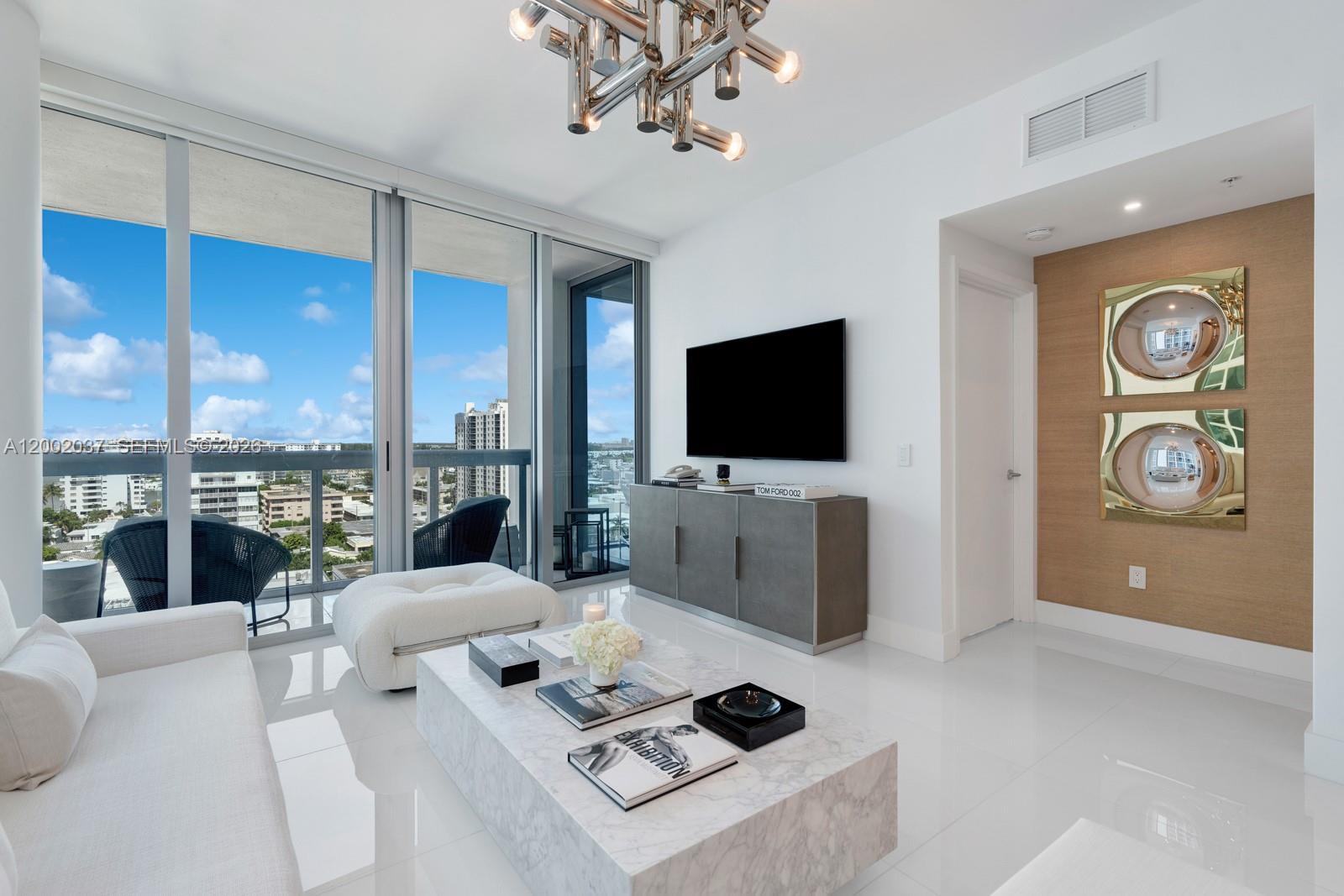 A modern living room features a marble coffee table, wall-mounted television, and floor-to-ceiling windows — 6899 Collins Ave # 1109, Miami Beach FL 33141, MIAMI BEACH, FL