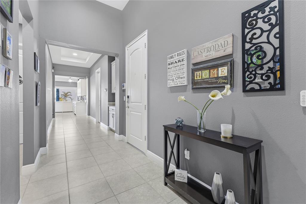A tiled entryway features a black console table, wall art, and a view into a kitchen — 13321 OAKENSHAW LANE, ORLANDO, FL