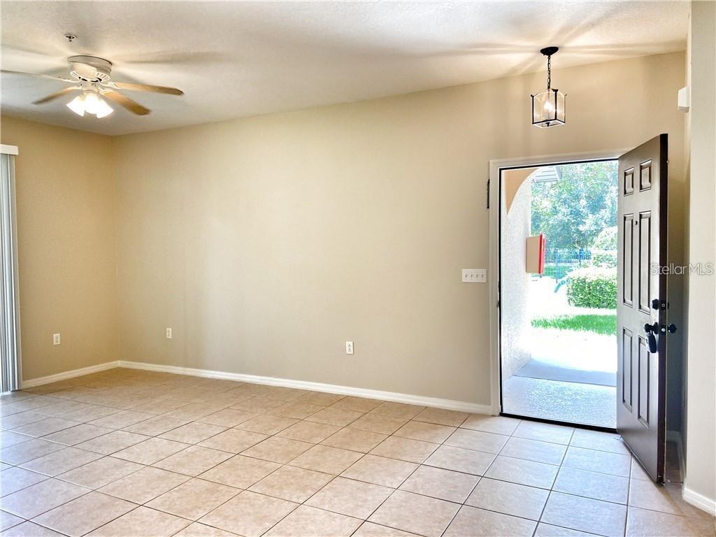 An interior view of a living room with tile flooring, a ceiling fan, and an open door — 4114 VIA PIEDRA CIRCLE UNIT 1-104, SARASOTA, FL