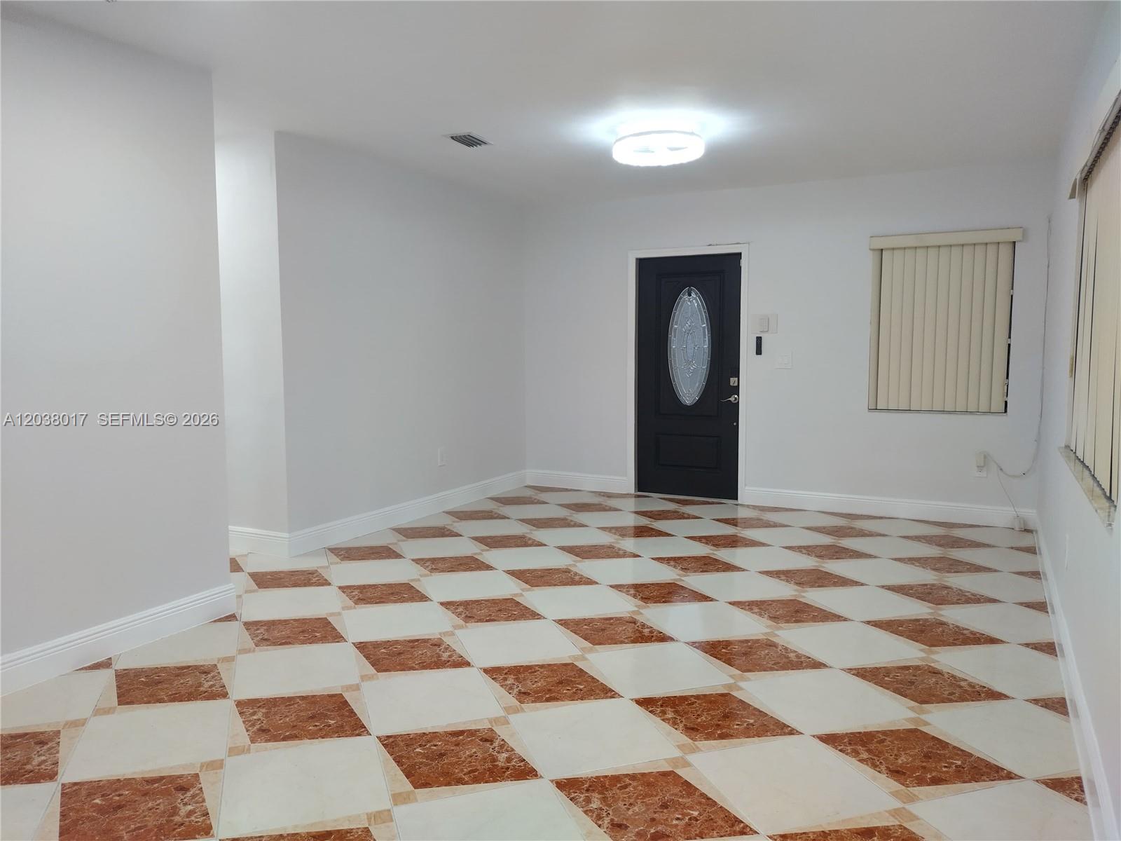 An empty room features white walls, a black front door, and a checkered tile floor — 265 NW 190th St, Miami Gardens FL 33169, MIAMI GARDENS, FL
