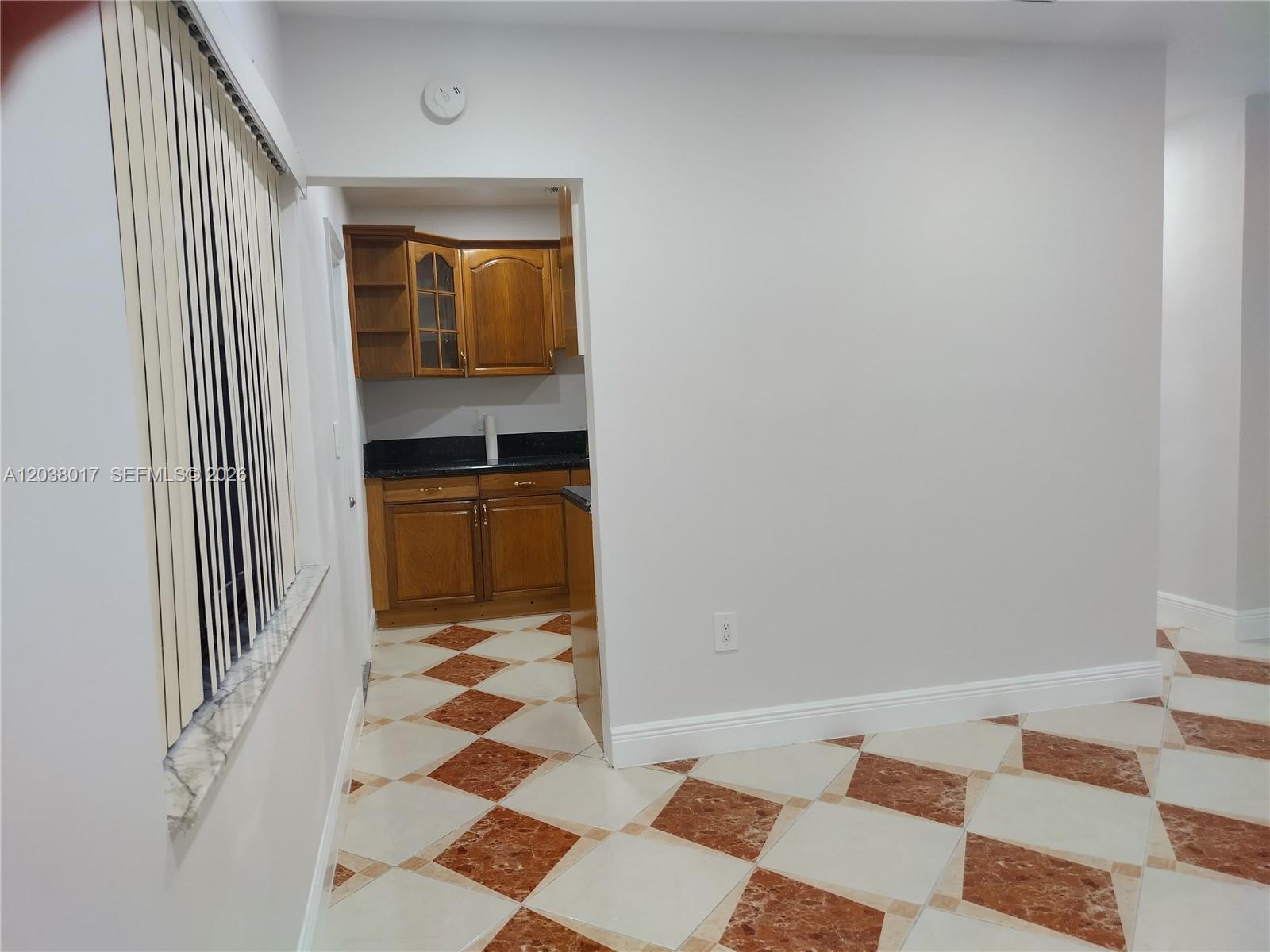 A kitchen with wood cabinets and dark countertops is visible through an opening from a room — 265 NW 190th St, Miami Gardens FL 33169, MIAMI GARDENS, FL