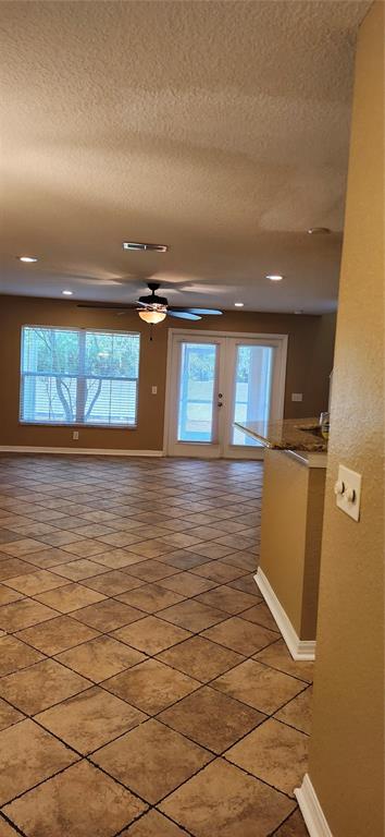 A room with tan tile floors, a ceiling fan, and a glass door leading outside — 2914 ROYAL TUSCAN LANE, VALRICO, FL