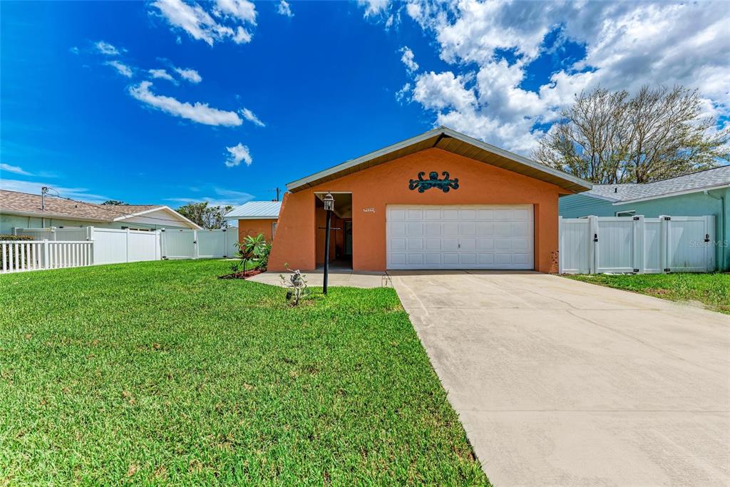 A single-story house with an orange stucco exterior, a two-car garage, and a white fence — 2406 15TH STREET W, PALMETTO, FL