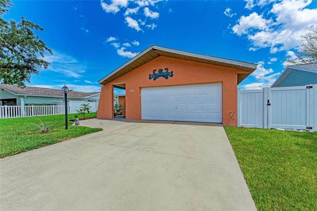 A single-story house with an orange stucco exterior, a white garage door, and a concrete driveway — 2406 15TH STREET W, PALMETTO, FL