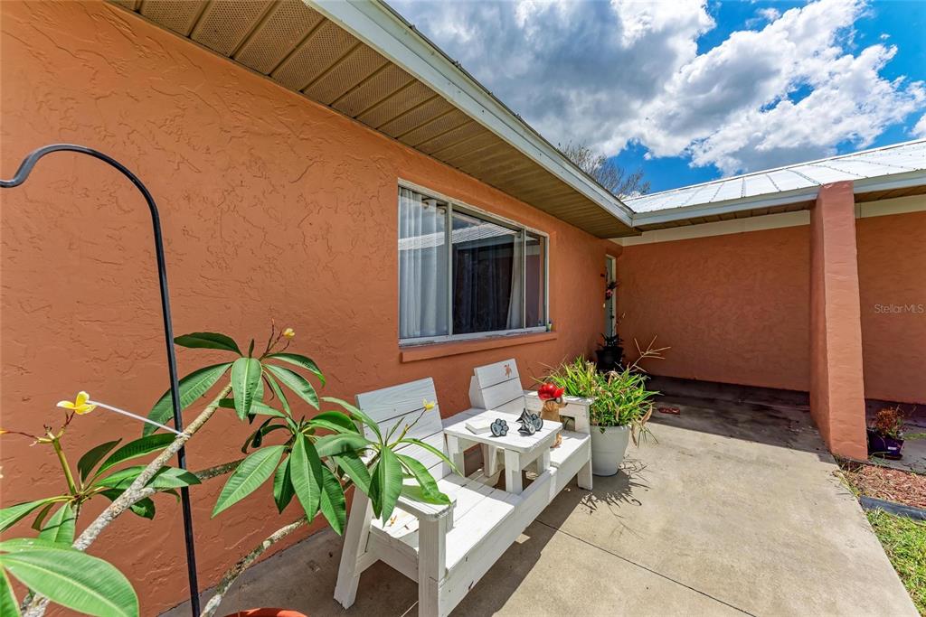 A white wooden bench sits on a concrete patio outside a peach-colored stucco house — 2406 15TH STREET W, PALMETTO, FL