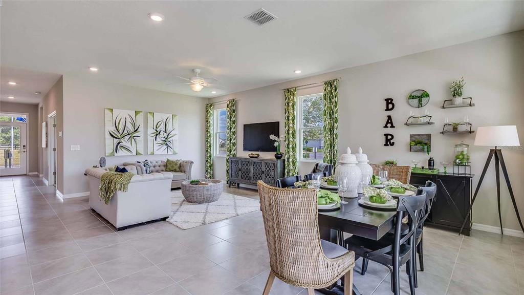 A living and dining area features tile flooring, a neutral color palette, and wicker furniture — 17295 SALTBUSH TRAIL, PARRISH, FL