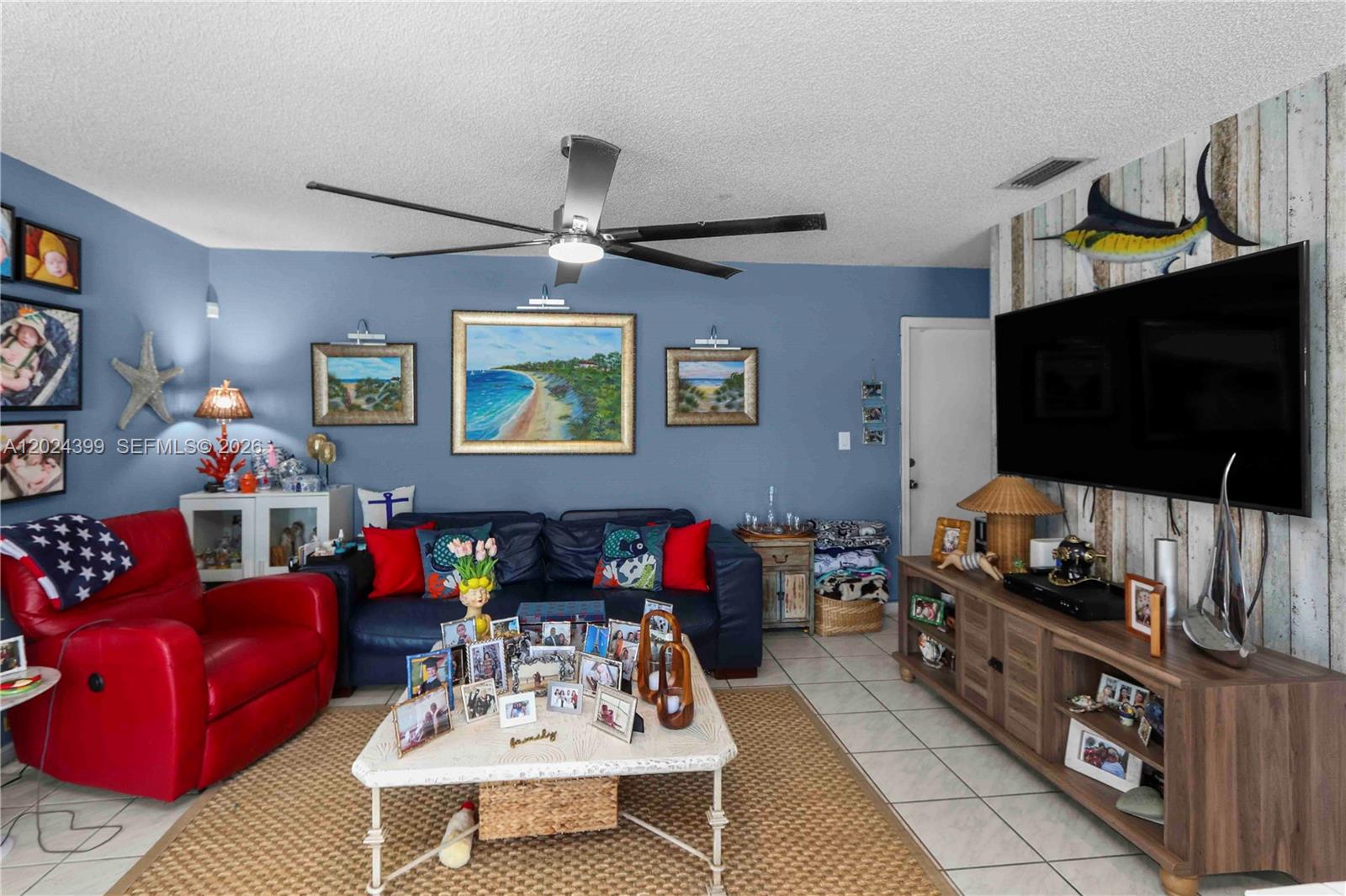 A living room features a blue wall, a dark sofa, a red recliner, and a television — 14454 SW 138th Ct, Miami FL 33186, MIAMI, FL