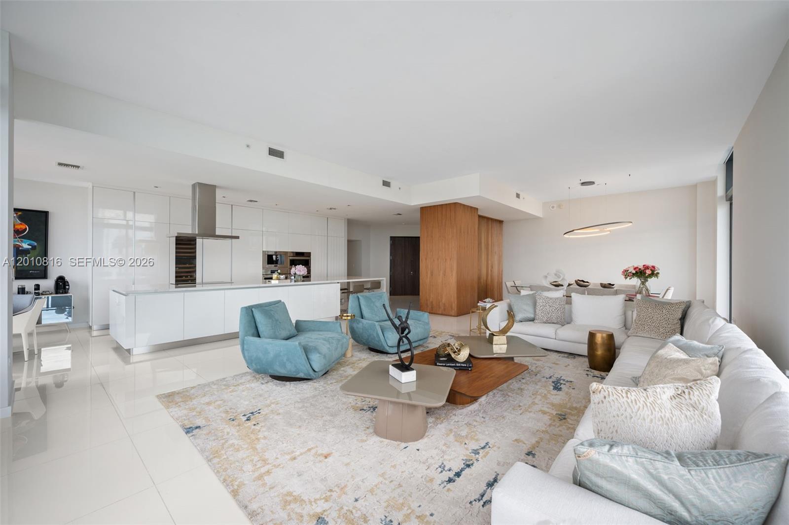 A modern open-concept living room features a white kitchen, blue armchairs, and a large sofa — 88 SW 7th St, Miami FL 33130, MIAMI, FL