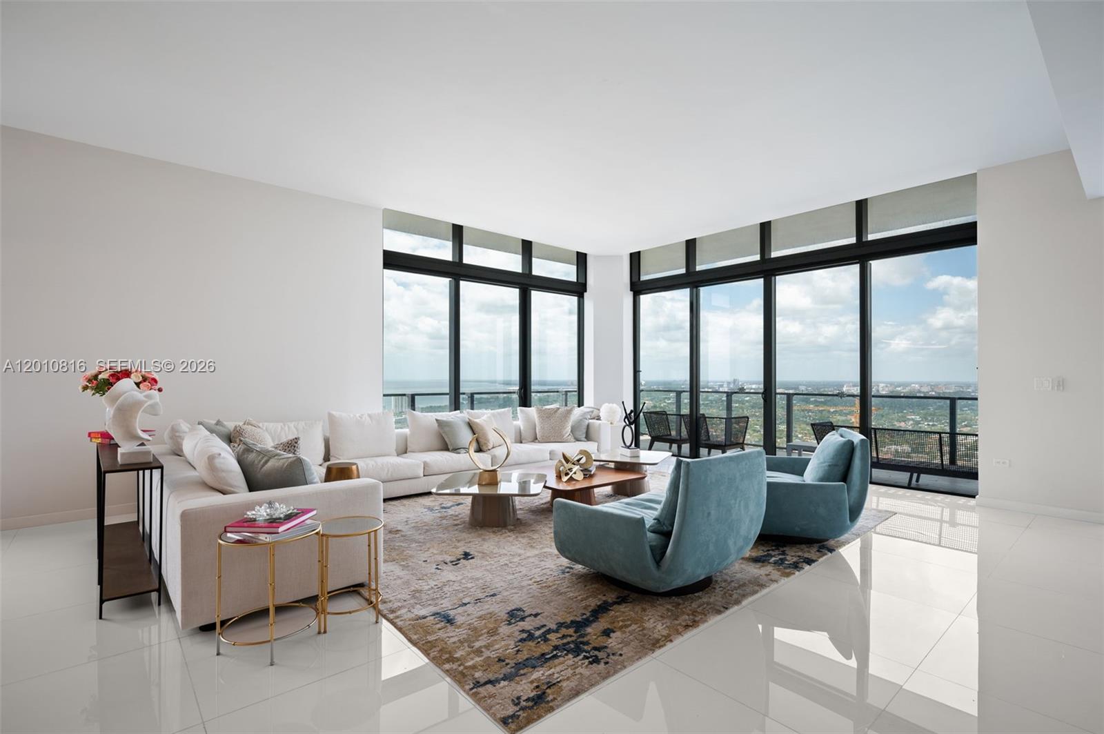 A modern living room features a large sectional sofa, two blue armchairs, and floor-to-ceiling windows — 88 SW 7th St, Miami FL 33130, MIAMI, FL