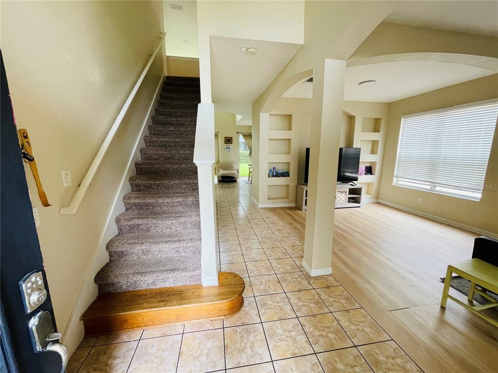 An entryway features a carpeted staircase, tiled flooring, and an open view into a living room — 1418 SPRING FEST LANE, ORLANDO, FL