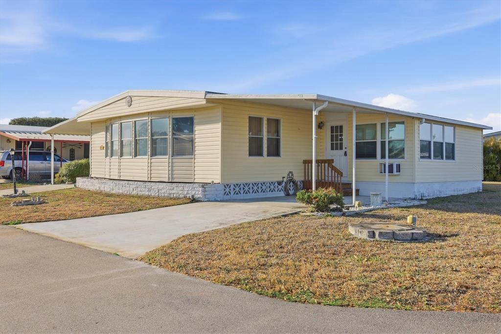 A single-story yellow mobile home with a concrete driveway and a covered front porch — 6710 36TH AVENUE E UNIT 201, PALMETTO, FL