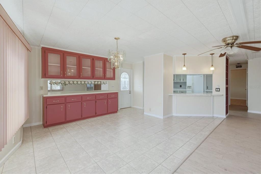 A dining area features red cabinetry, a mirrored backsplash, tile flooring, and a ceiling fan — 6710 36TH AVENUE E UNIT 201, PALMETTO, FL