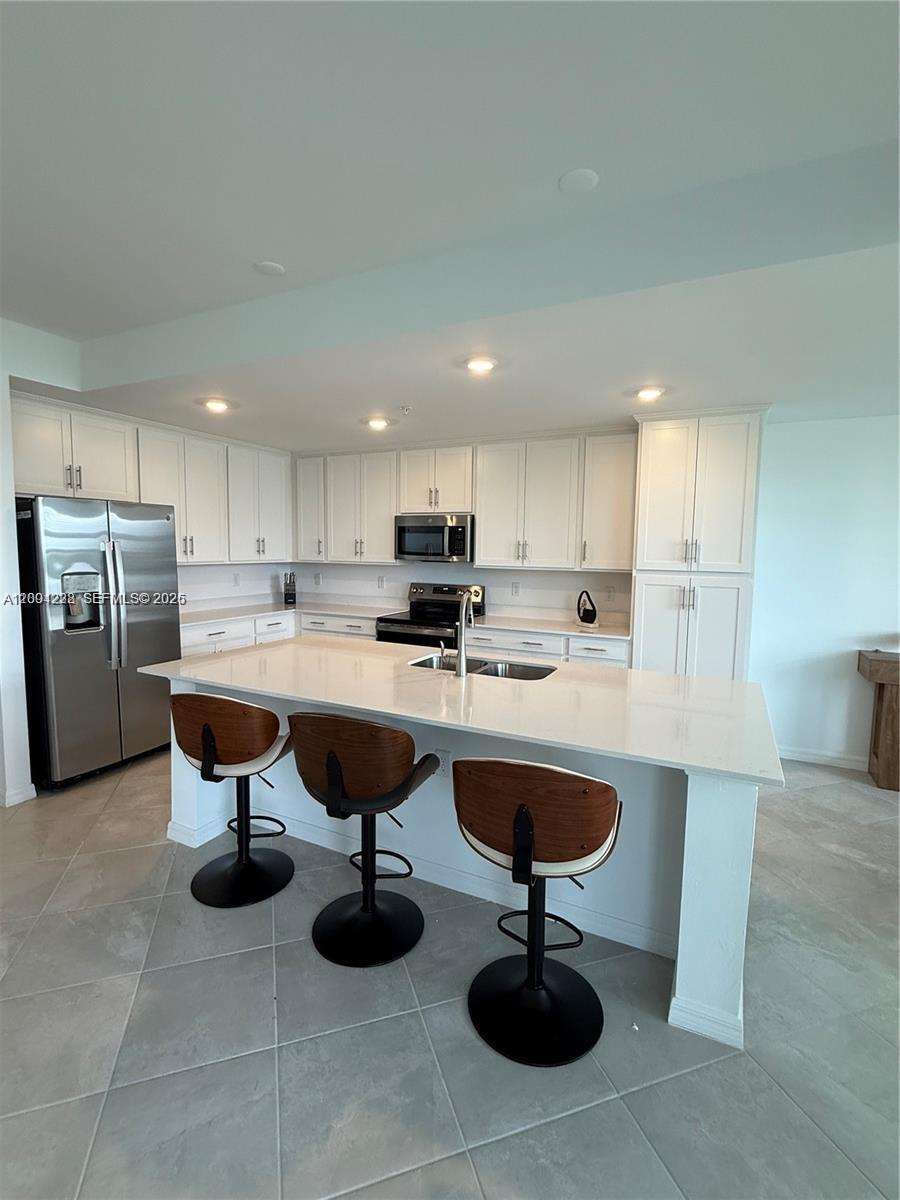 A modern kitchen features white cabinetry, stainless steel appliances, and a large central island — 5555 Double Eager Circle # 3917, Ave Maria FL 34142, AVE MARIA, FL