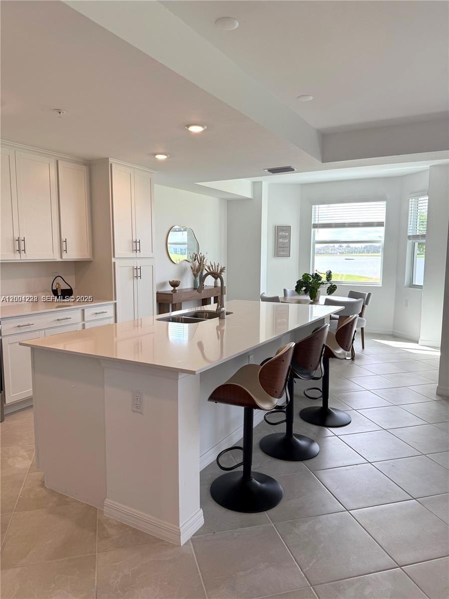 A modern kitchen features a large white island with bar stools and tile flooring — 5555 Double Eager Circle # 3917, Ave Maria FL 34142, AVE MARIA, FL