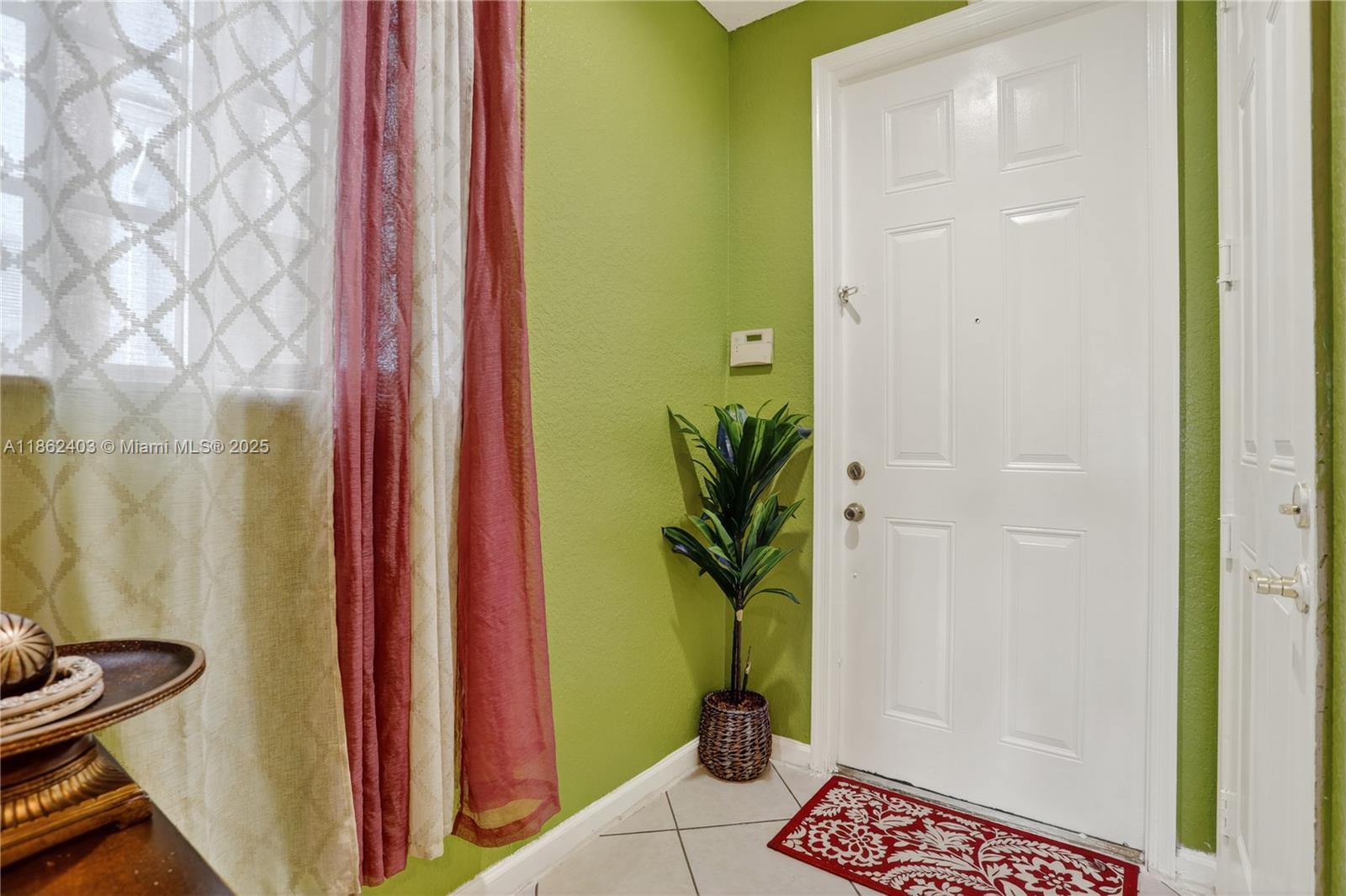 An entryway features green walls, a white door, a potted plant, and a red rug — 3445 NW 14th Ct, Lauderhill FL 33311, LAUDERHILL, FL