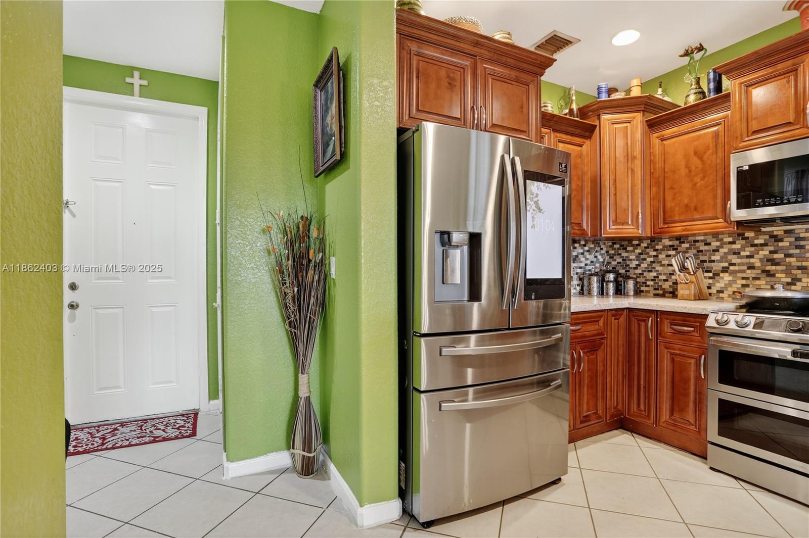 A kitchen features stainless steel appliances, wood cabinetry, and a bright green accent wall — 3445 NW 14th Ct, Lauderhill FL 33311, LAUDERHILL, FL