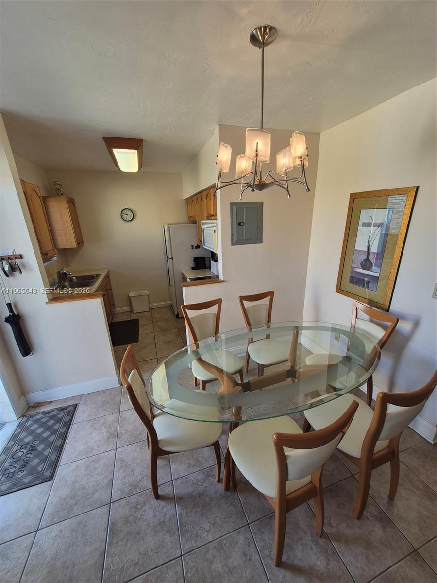 A dining area with a glass table and chairs sits adjacent to a small kitchen — 520 Euclid Ave # 8, Miami Beach FL 33139, MIAMI BEACH, FL