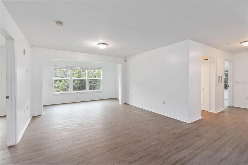 An empty room with white walls, light wood-look flooring, and a large window — 5459 VINELAND RD UNIT 4208, ORLANDO, FL