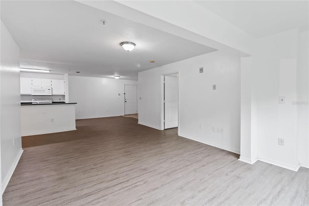 An open-concept living area features light wood-look flooring, white walls, and a kitchen with white cabinets — 5459 VINELAND RD UNIT 4208, ORLANDO, FL
