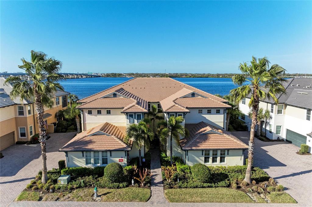 An aerial view of waterfront residential buildings along a mangrove-lined coast with a nearby marina — 1246 RIVERSCAPE STREET, BRADENTON, FL