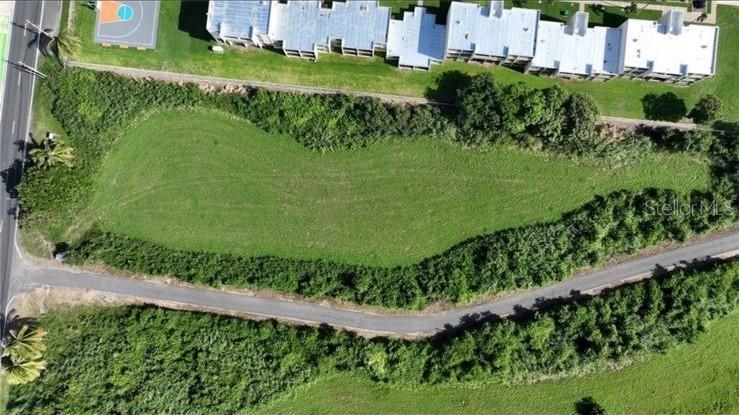 This is an aerial view of a vacant, grassy lot bordered by roads and buildings — CARR 485 KM 1.7 BO. MEMBRILLO, CAMUY, PR
