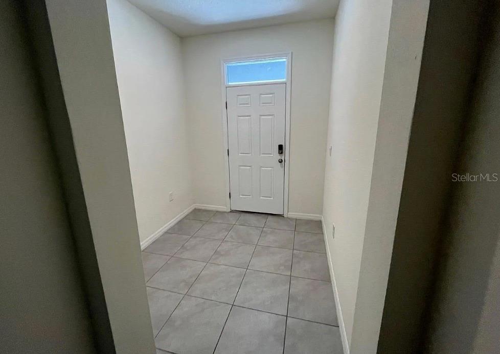 An entryway features light gray tile flooring, white walls, and a white front door — 32867 PEZ LANDING LANE, WESLEY CHAPEL, FL