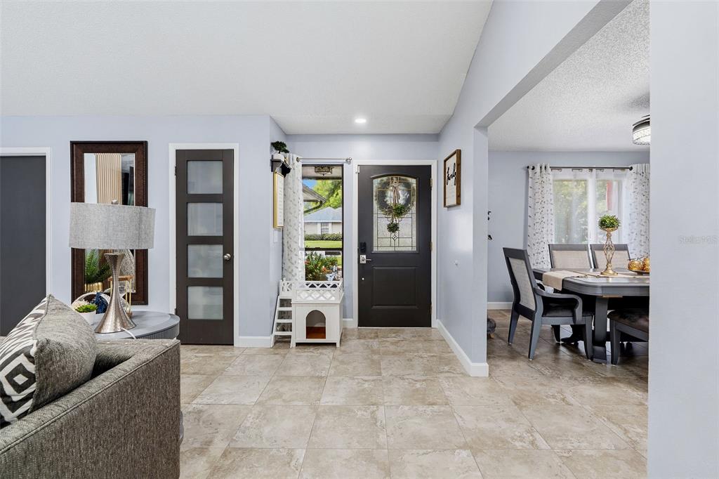An entryway with tile flooring leads to a dark front door and a dining area — 15747 SCRIMSHAW DRIVE, TAMPA, FL