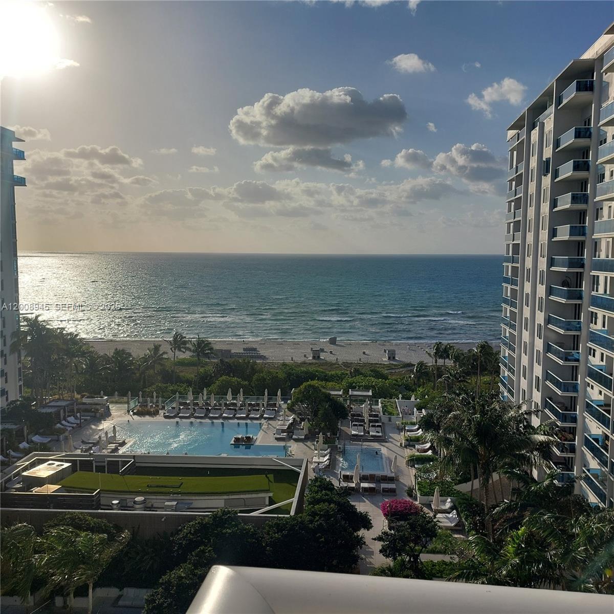 An elevated view of a swimming pool area, beach, and ocean between two high-rise buildings — 2301 Collins Ave # 1125, Miami Beach FL 33139, MIAMI BEACH, FL