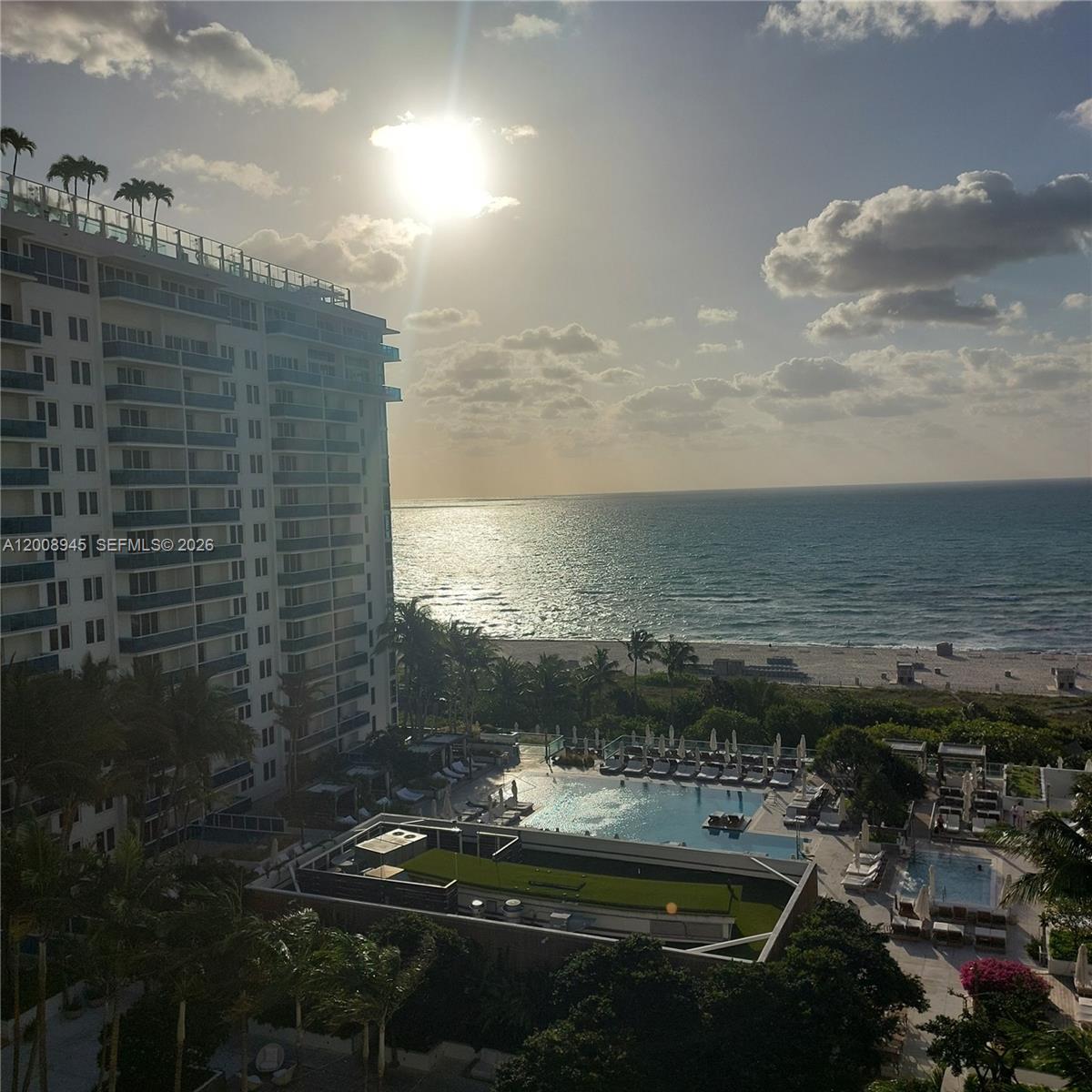 An elevated view shows a tall beachfront condominium building overlooking a pool deck and ocean — 2301 Collins Ave # 1125, Miami Beach FL 33139, MIAMI BEACH, FL