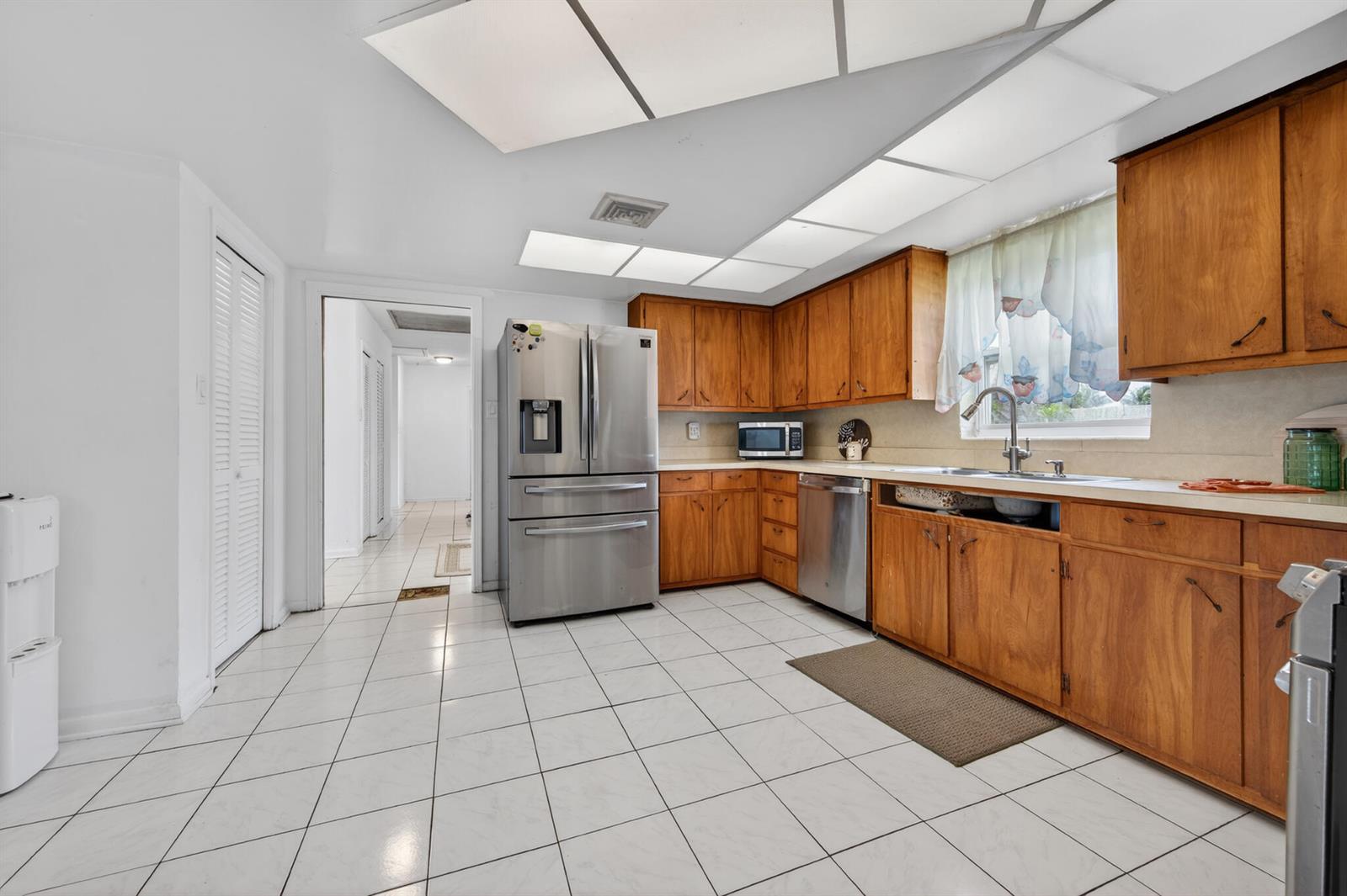 A kitchen with wood cabinets, stainless steel appliances, and white tile flooring — 360 Kismet Avenue, Pahokee FL 33476, PAHOKEE, FL
